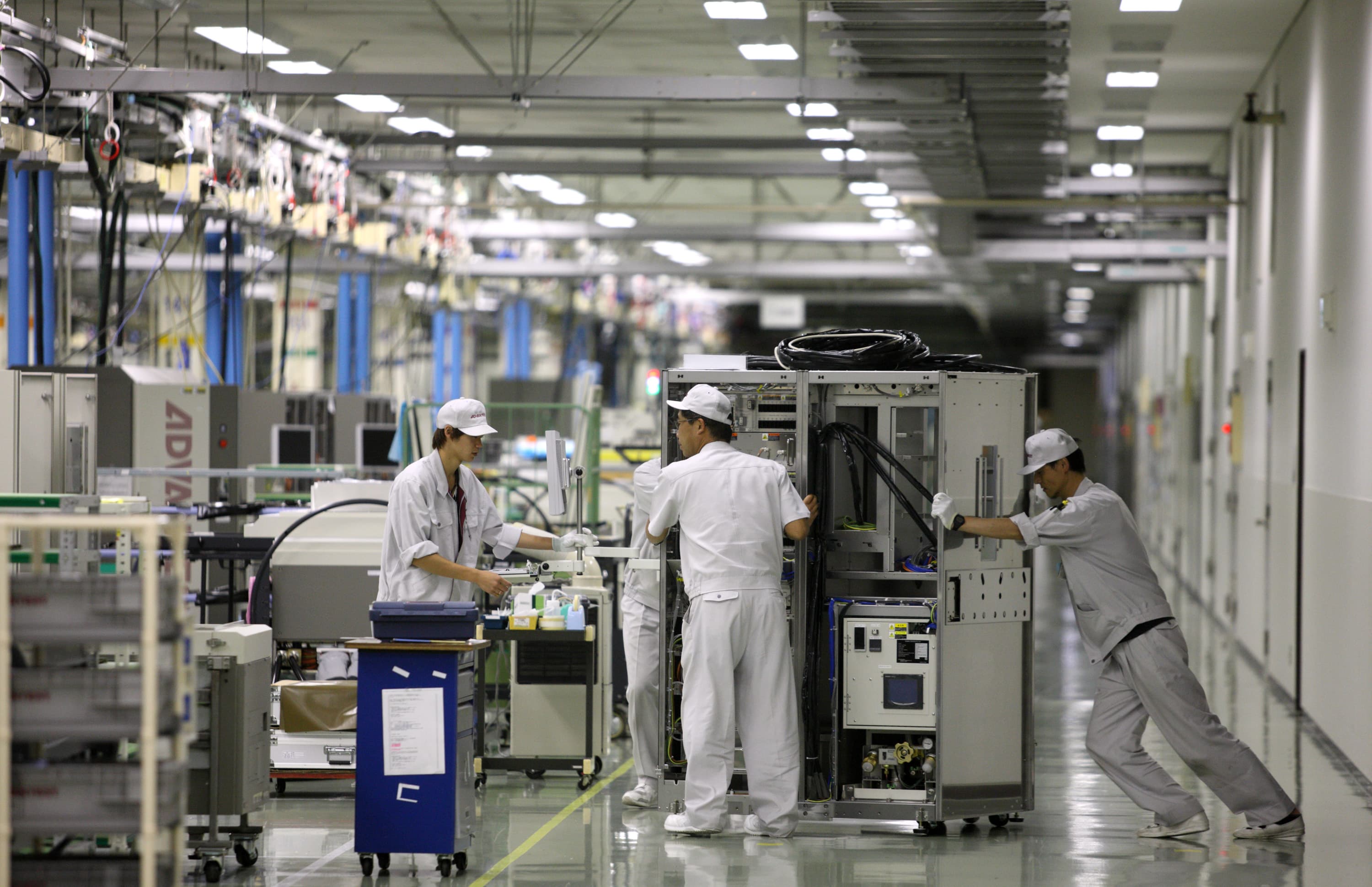 Employees move semiconductor testers on the assembly line of the Advantest Corp. plant in Ora, Japan on Aug. 10, 2012.